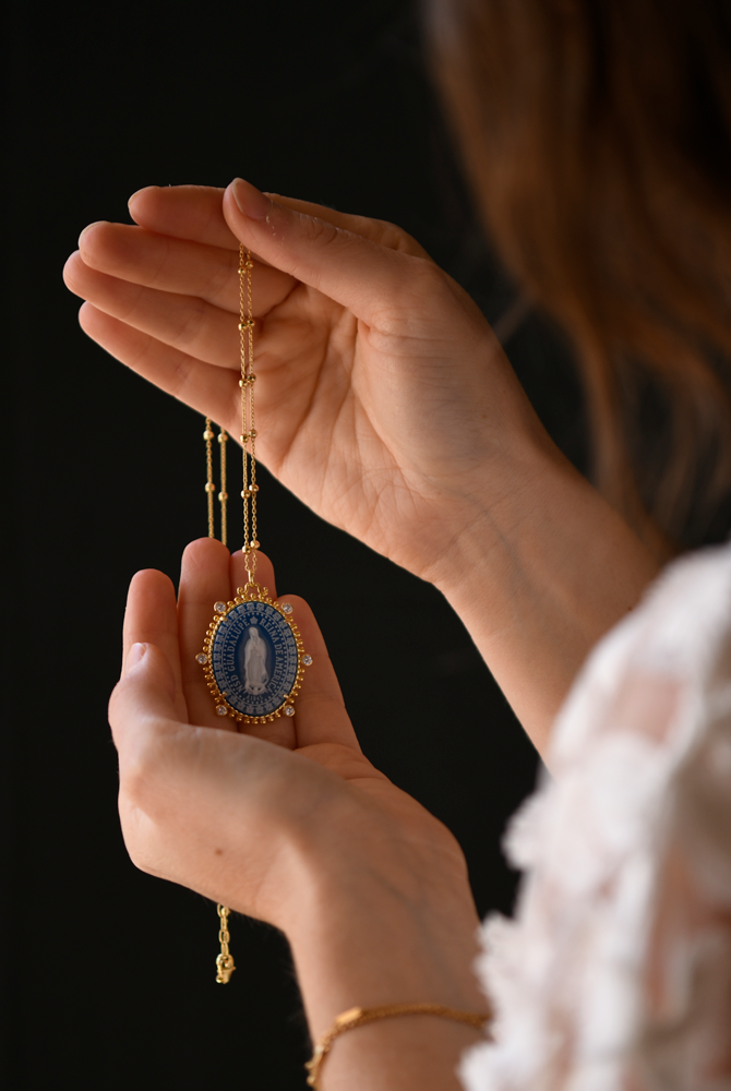 lady holding up the virgin of Guadalupe Reina medallion